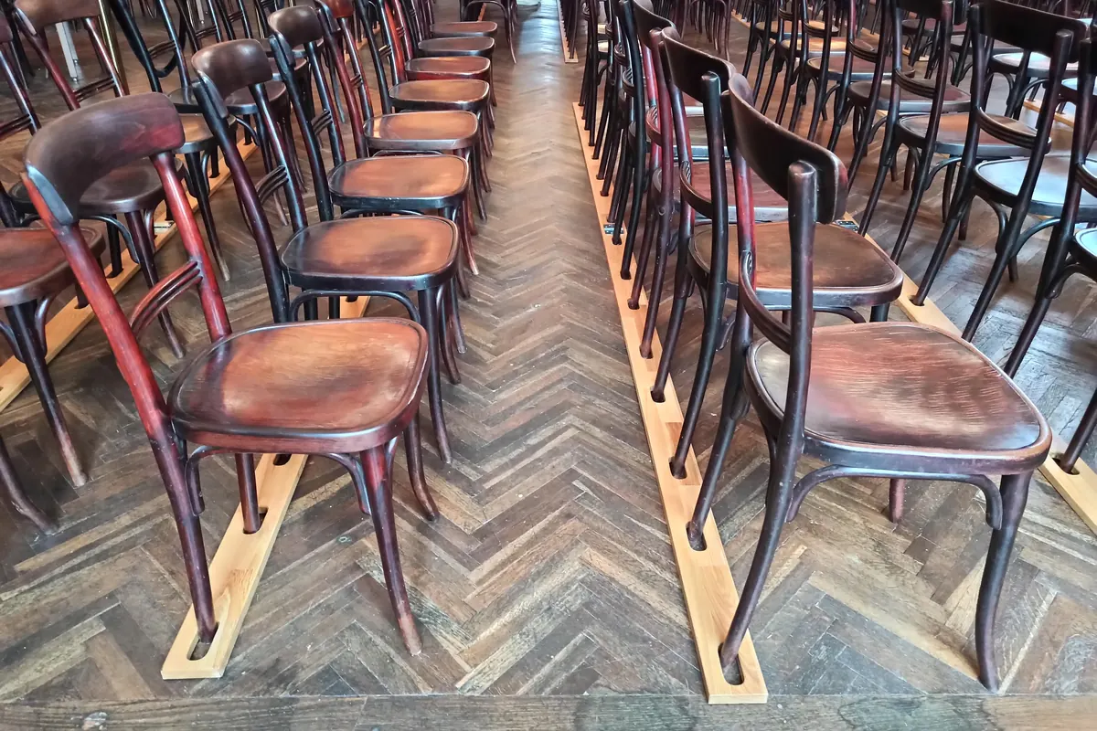 Rows of dark bentwood chairs with curved backs and wooden seats standing on a herringbone parquet floor